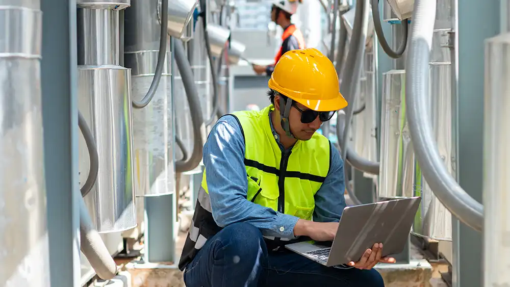 HVAC Student kneeling in front of outdoor HVAC system