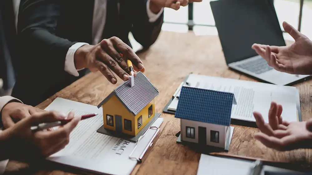Real estate professional touching model house with hand and pen
