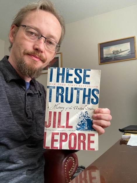 A man holding up the book These Truths by Jill Lepore