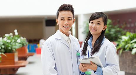 Two individuals in lab coats smiling for the camera.