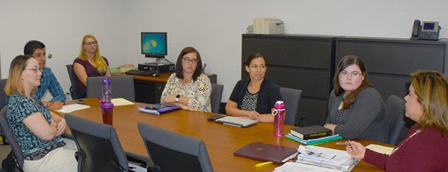 Individuals having a meeting while sitting at a conference table.