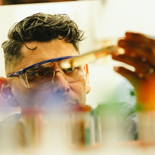 A scientist looking at a liquid in a test tube in a lab.