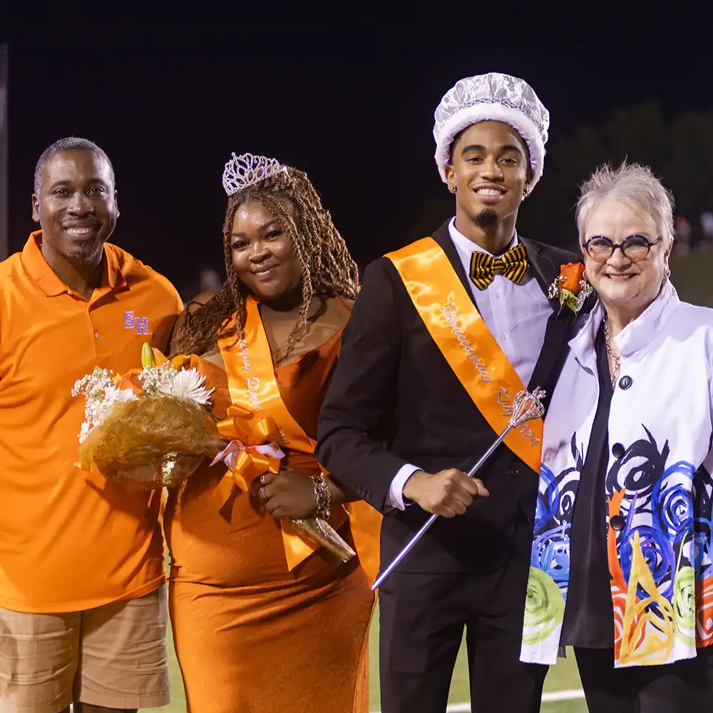 VP Dr. Moore, Homecoming King and Queen and President Dr. White on the field during crowning.