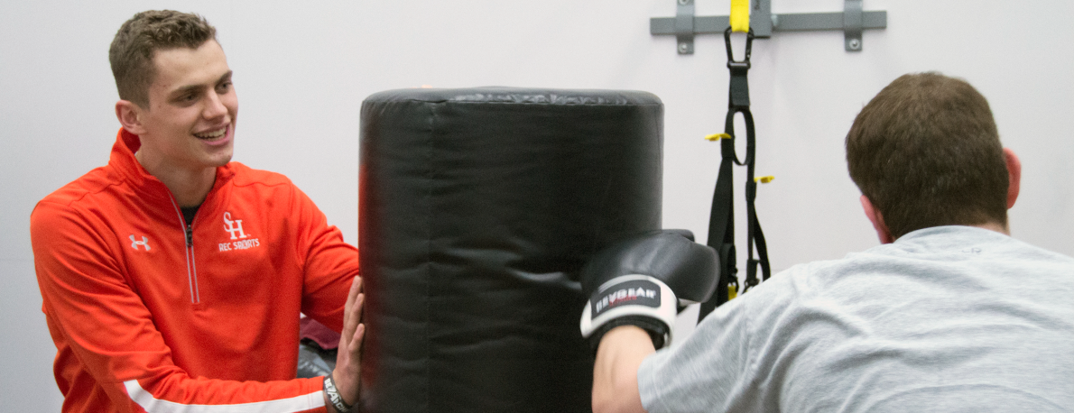 trainer holding punching bag while trainee hits it