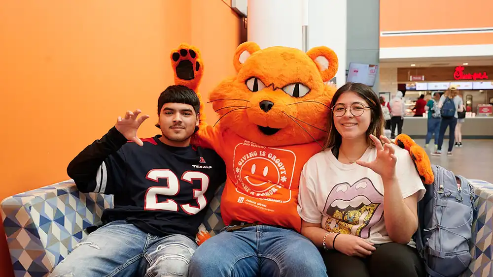 Two students sitting with Sammy