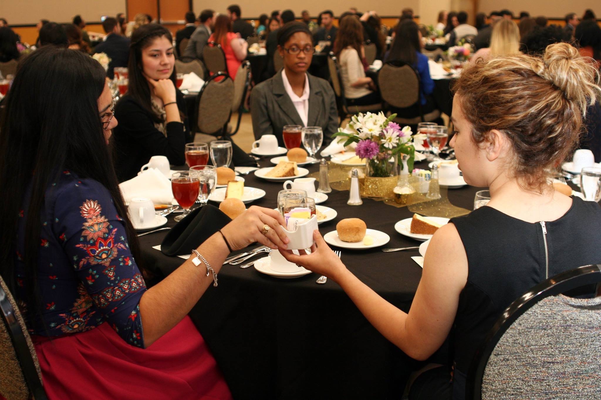 Students pass something between themselves at the Etiquette Dinner.