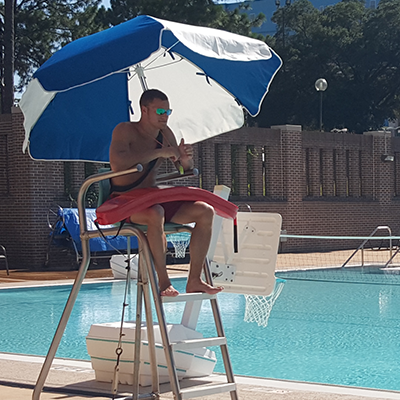 Lifeguard sitting in station watching over pool