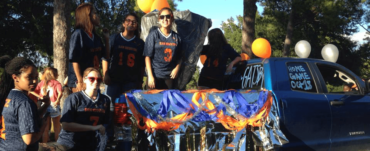 womens lacrosse team in back of truck during homecoming parade