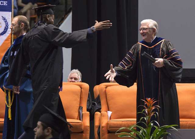 Provost Dr. Richard Eglsaer happily gives an excited student his diploma as he walks across the stage.