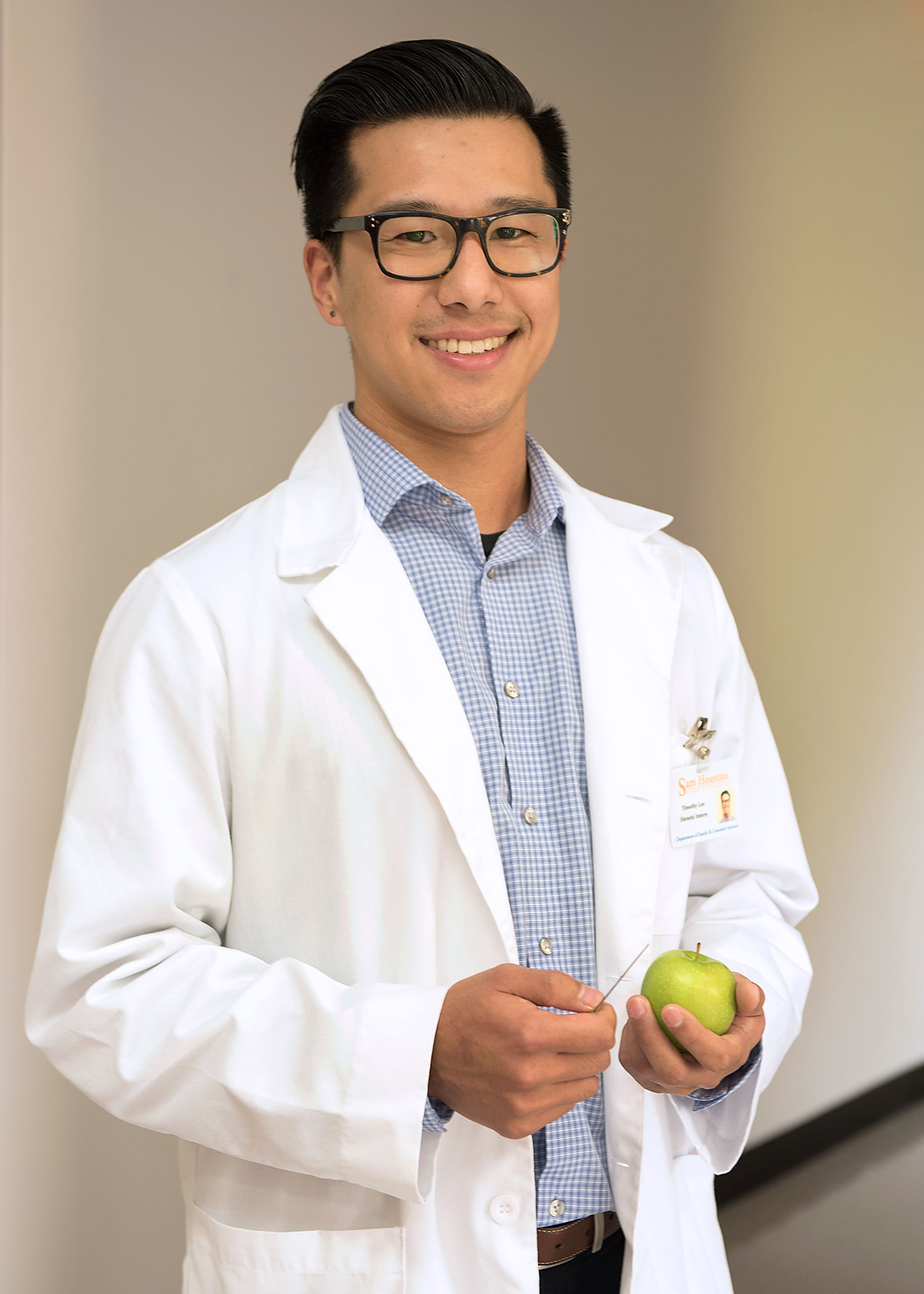 Student wearing a lab coat, holding a green apple