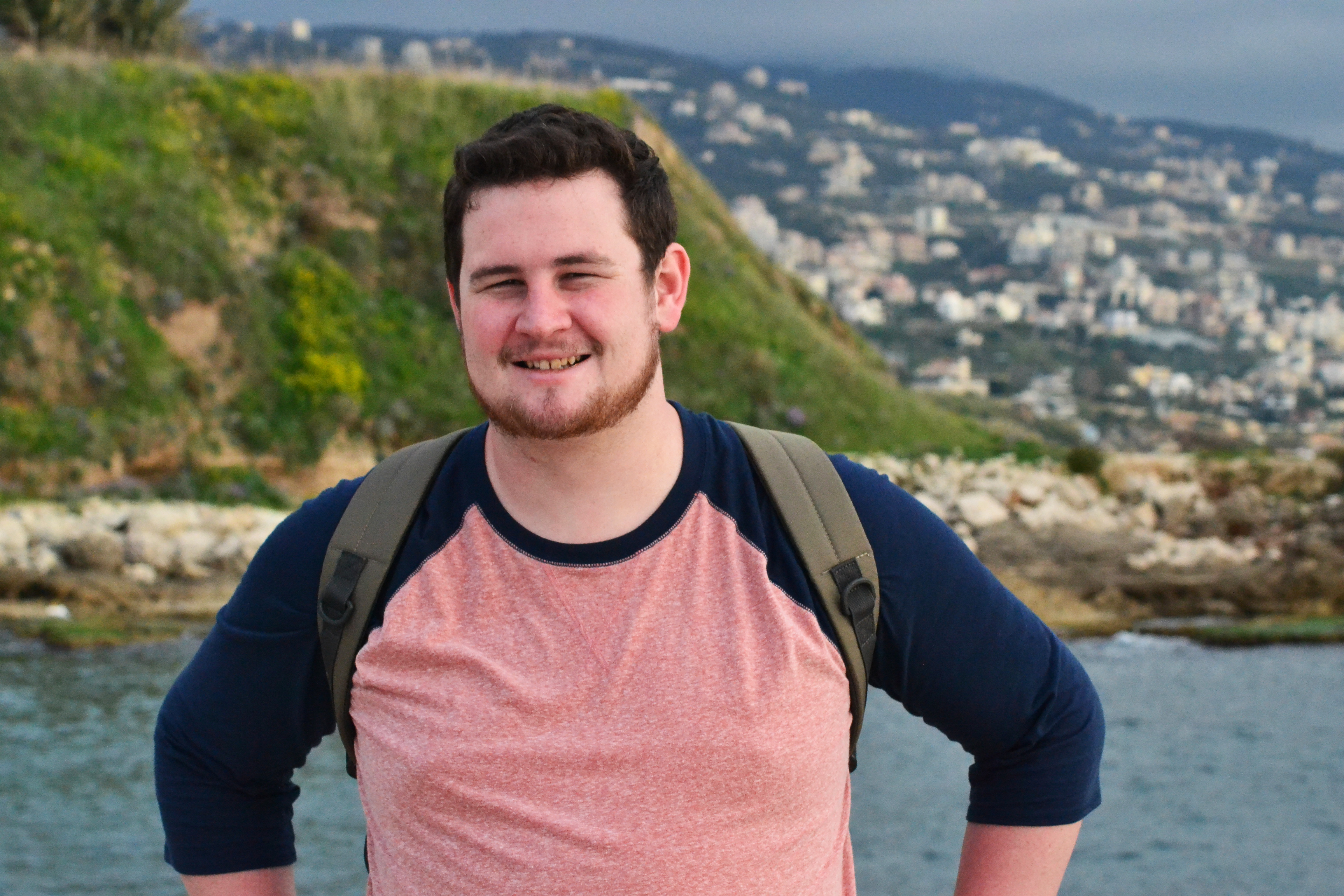 Connor posing in front of a seaside town in Europe