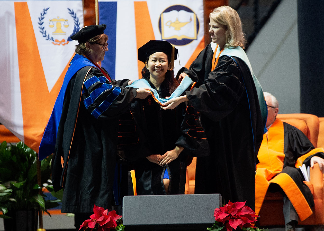 A hood is placed upon a doctoral student.
