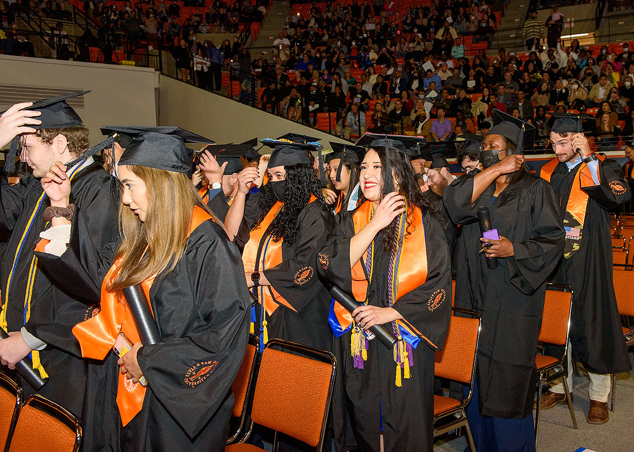 Graduates grab the tassels on their caps in preparation to turn them to the opposite side.