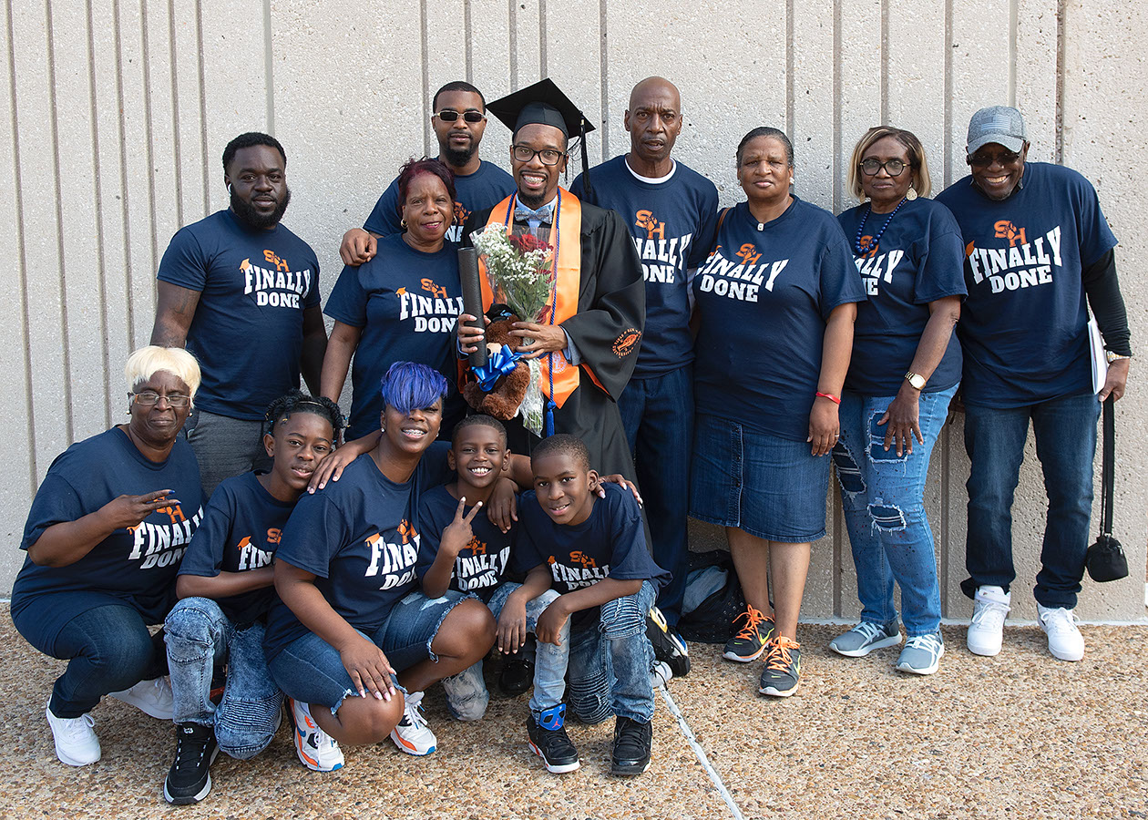 A large family group photo with a graduate. Everyone in the family of 12 is wearing a shirt that says Finally Done on it.