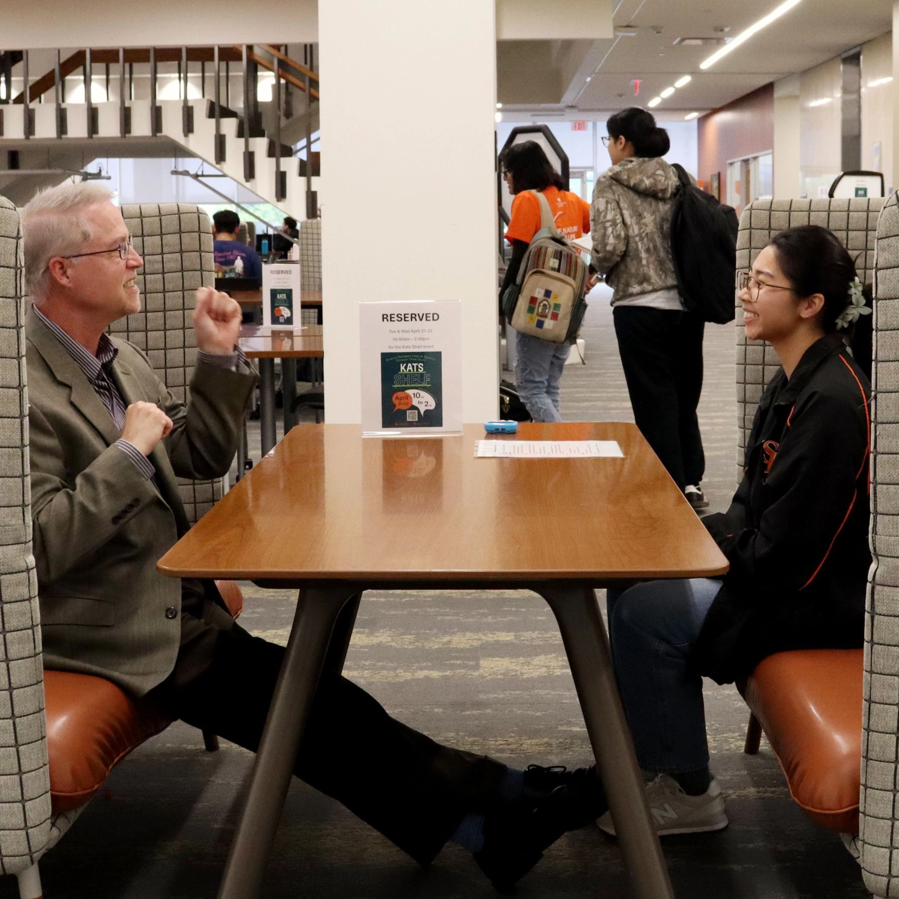 Students interact with faculty member in library. 