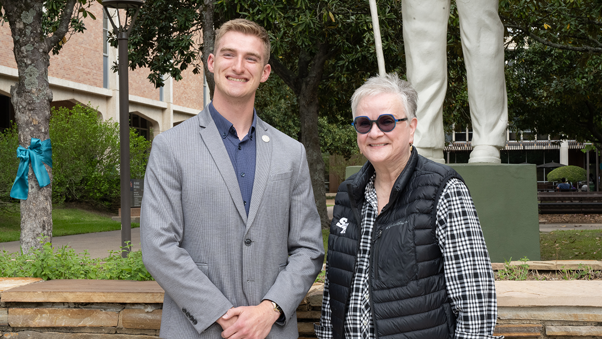 Kaleb smiles and poses with President White in front of one of the Sam Houston statues on campus.