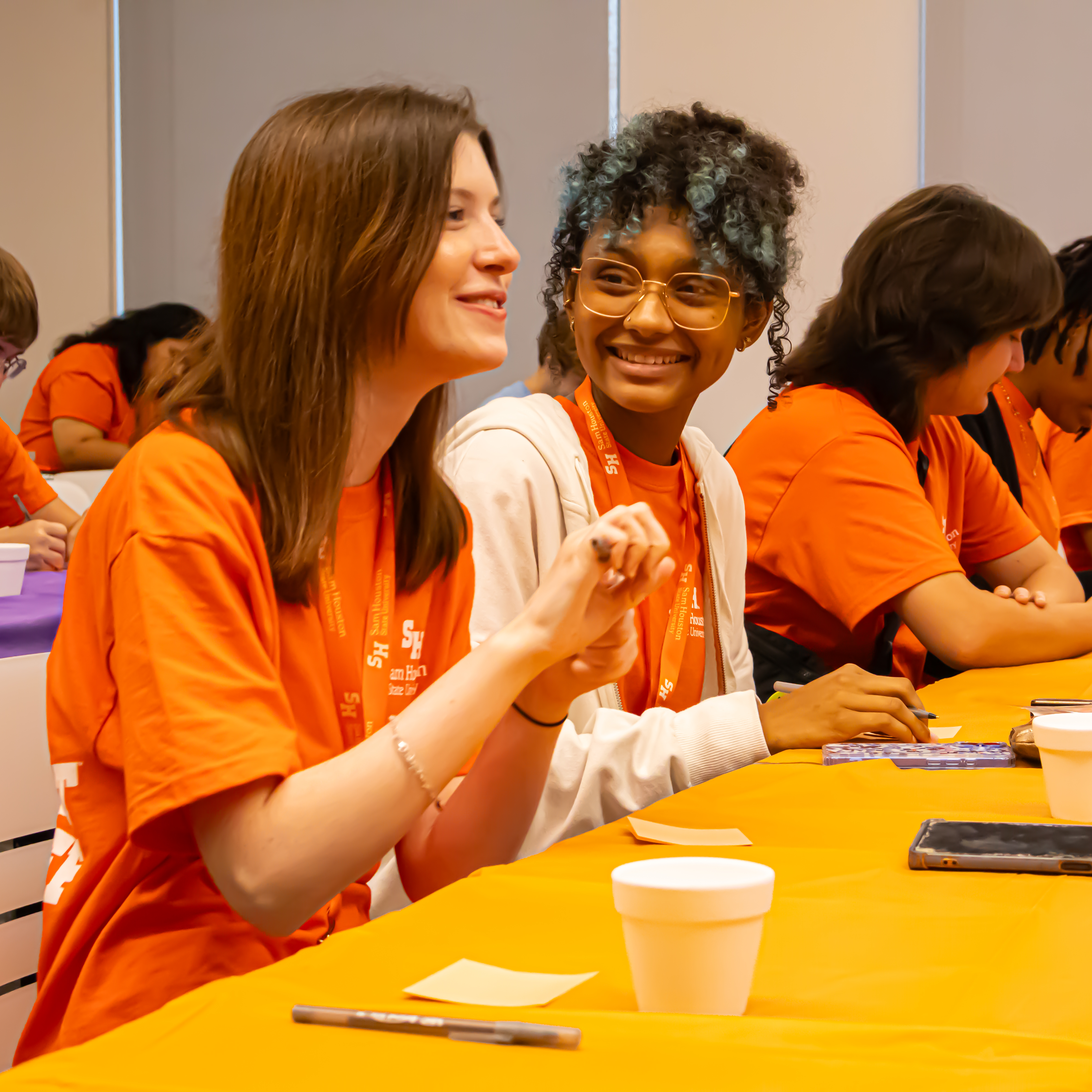 students smile and paint pots for succulents.
