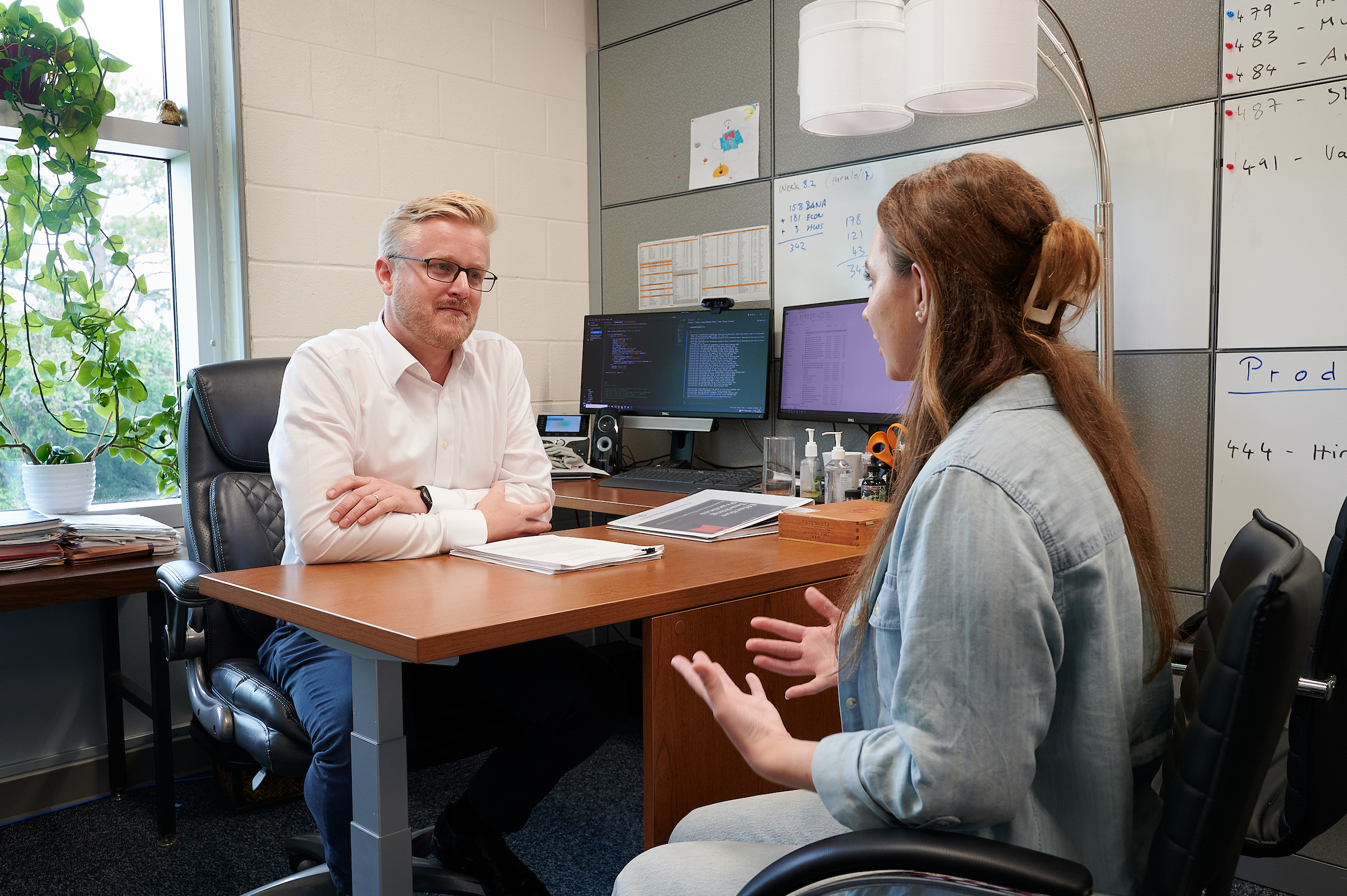 Faculty sitting at desk with student