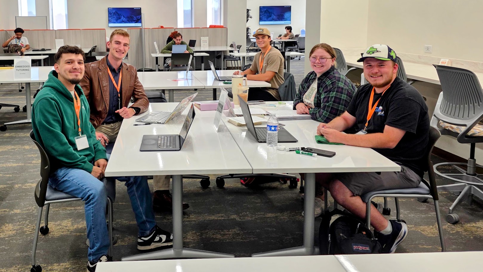 five ambassadors at a dry erase table with laptops in front of them.