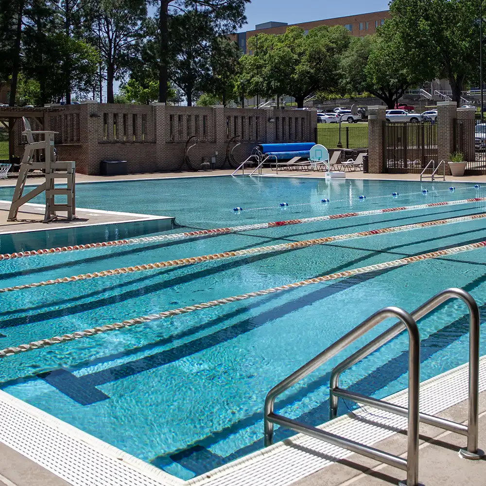 Outdoor picture of the pool in the daylight with a surrounding gate.