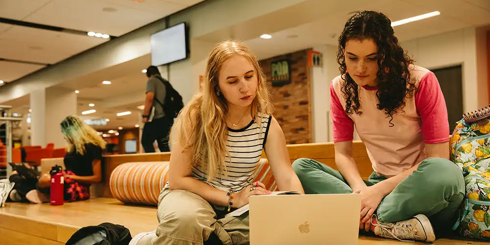 Two SHSU students using a laptop in the Lowman Student Center.