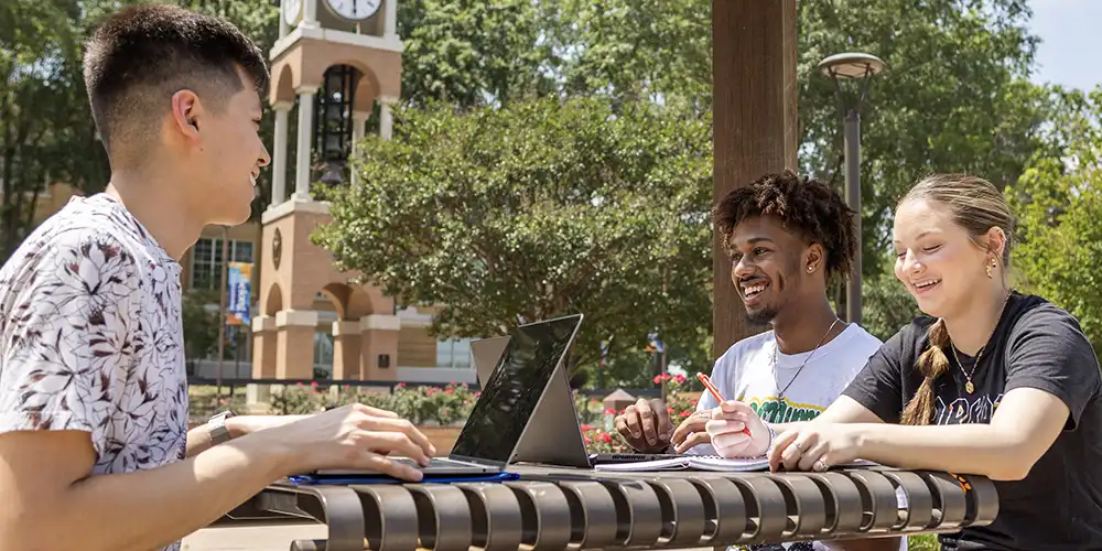Students sitting outside at table talking