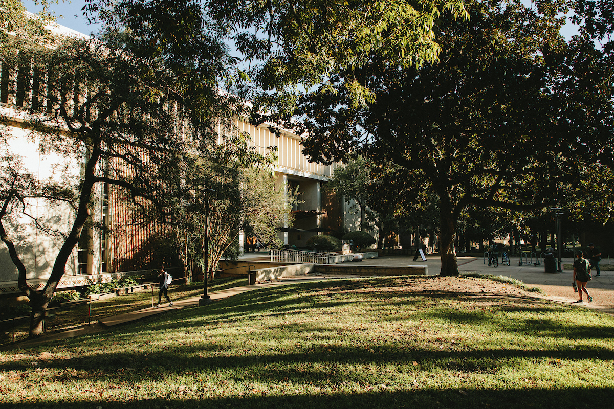 ​​Azaleas blurred in front of the Blatchley Bell Tower on a sunny blue sky day.​ 