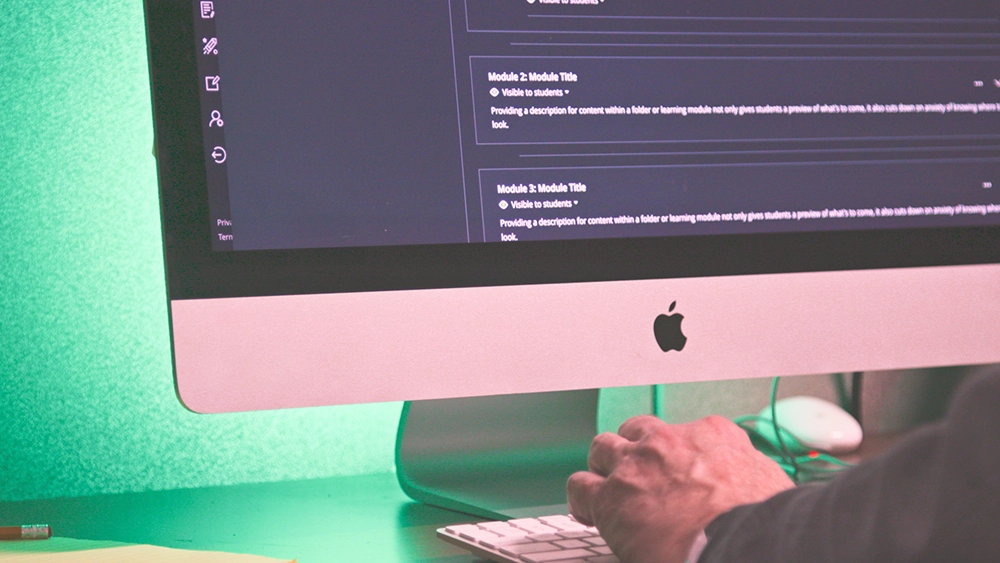 Hands on a keyboard with the wall behind a monitor lit up with green light.
