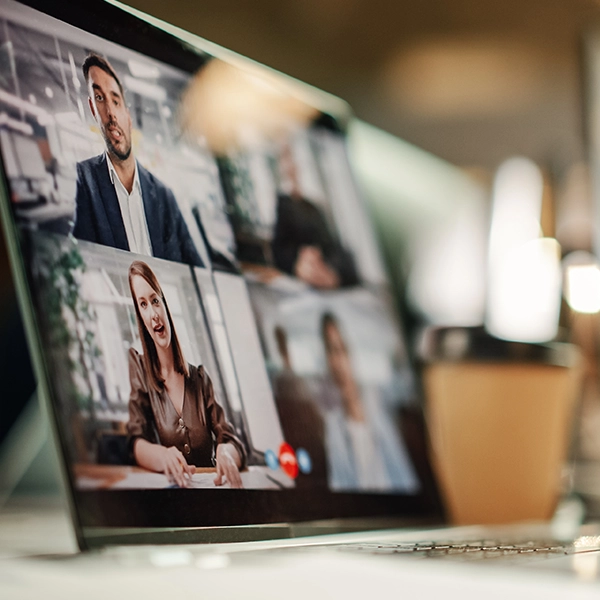 An angled view of a laptop screen showing a four-person video conference