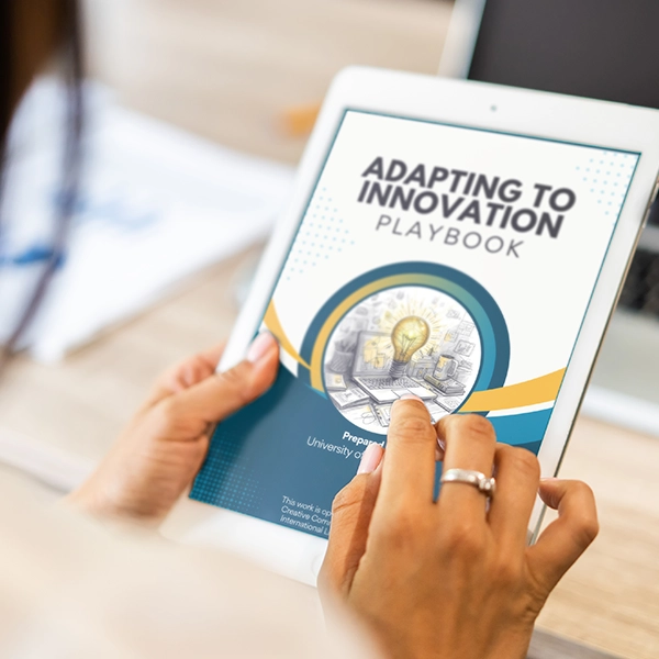 A person holding a tablet displaying the "Adapting to Innovation Playbook" cover