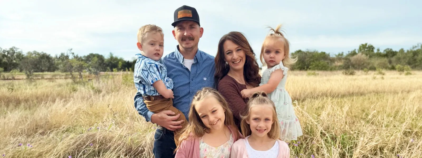 Mariah Howell Basinger, her husband, and four children in a picturesque field on easter Sunday