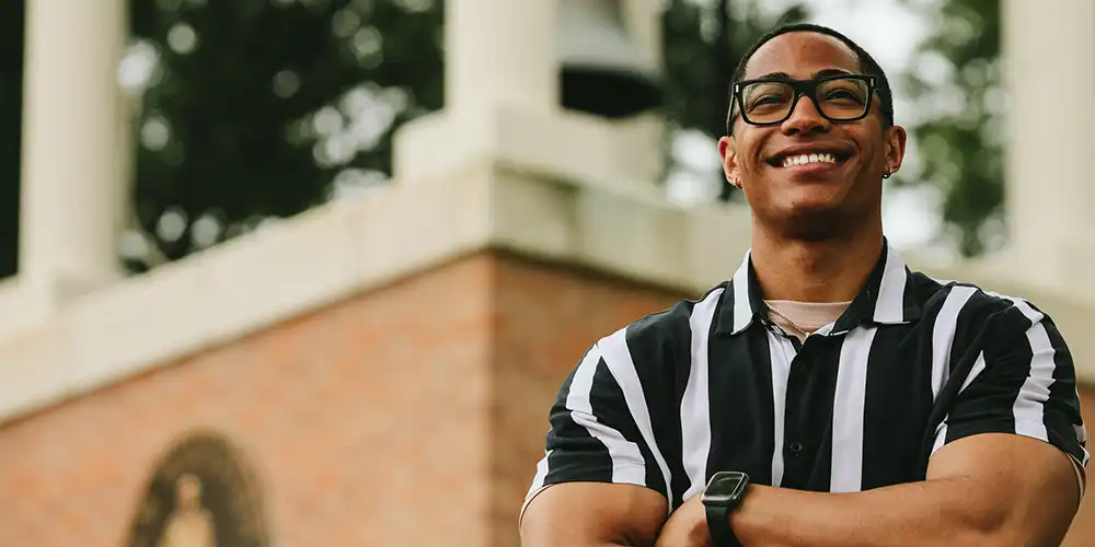 Photo of student smiling in front of the bell tower on campus