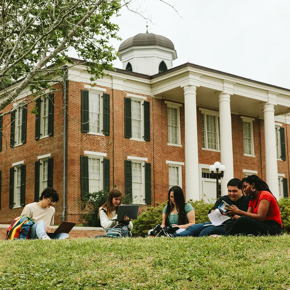 People looking at each other, smiling, sitting down, working on an assignment.