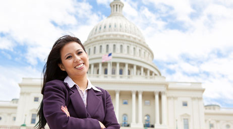 A woman stands in front of the capitol building of the United States of America.