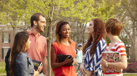 A group of students conversing in front of trees and buildings at Sam Houston State University.