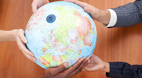 A group of students have their hands on a globe.