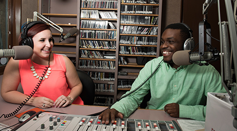 Two students recording in a sound booth.