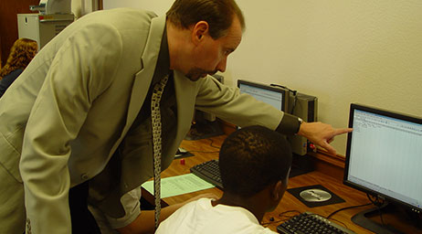 An instructor is guiding an accounting student who is using a computer.