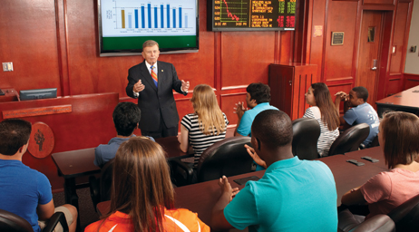 A business professor is instructing a group of students in a classroom.