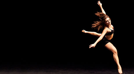 A student dancing against a black bacground.