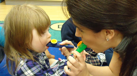 A student is using kazoos to provide music therapy for a patient.