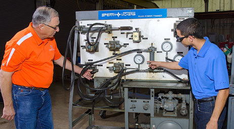 A sam houston state university student is getting instruction from a professor about a large machine.