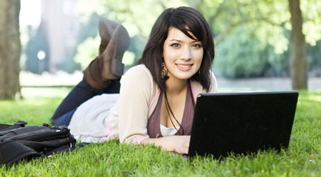 A woman is using a laptop in an outdoor setting.