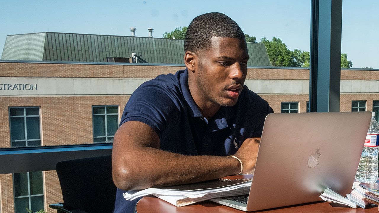 A college student using a laptop in an indoor setting.