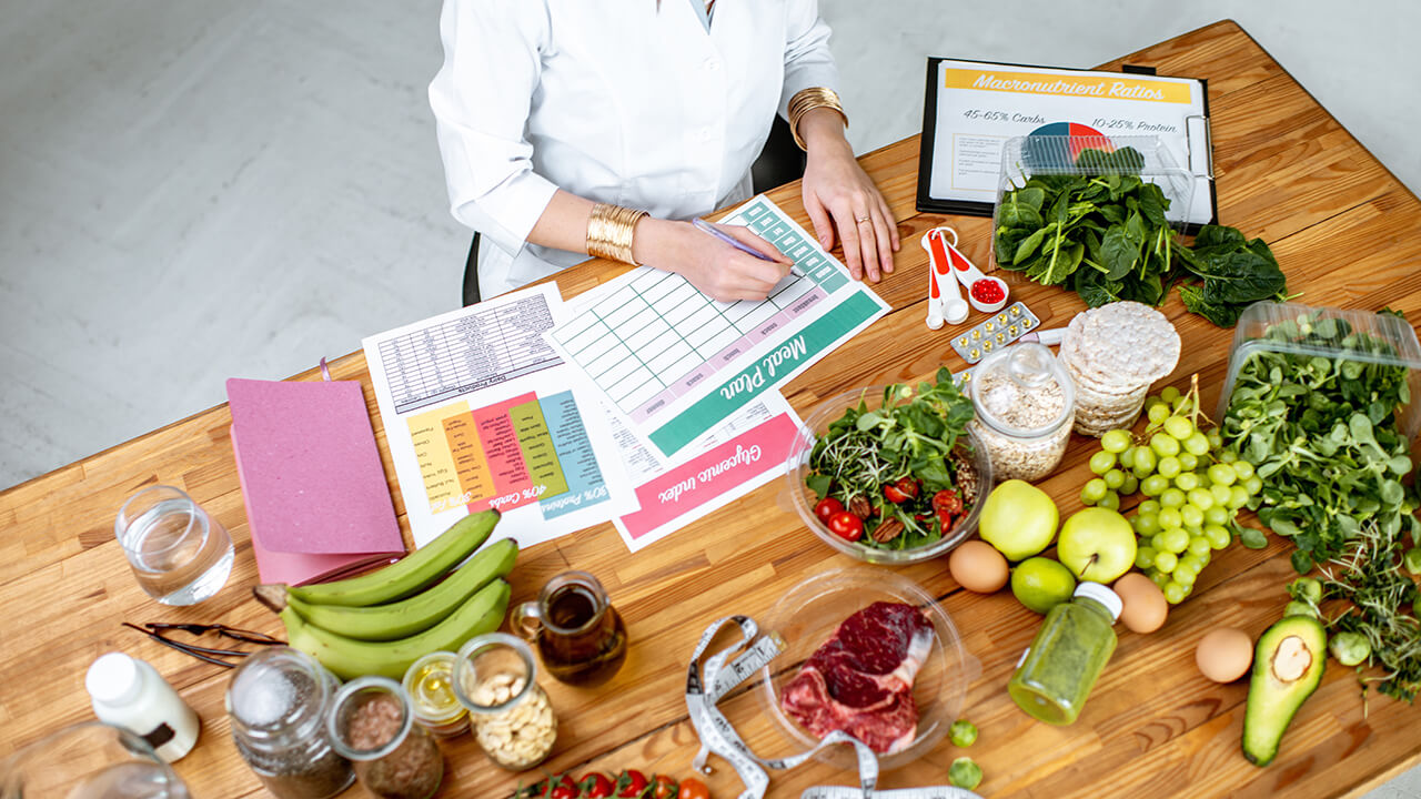 A nutritionist creating a menu at a table containing vegetables.