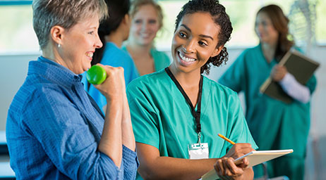 A person in medical scrubs is observing another person.