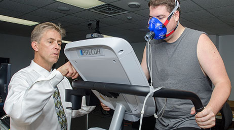 A researcher tracks a subject on a treadmill.