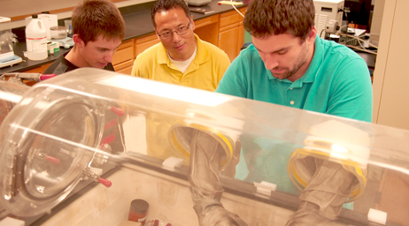 A student is using protective equipment in a physics laboratory while conducting research.