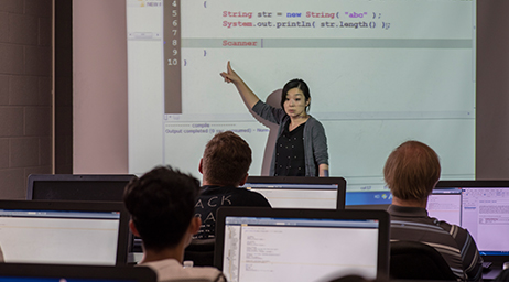 An instructor is teaching a group of students code in a classroom environment.