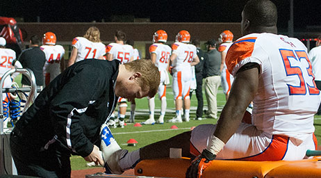 An athletic trainer working with an athlete's leg.